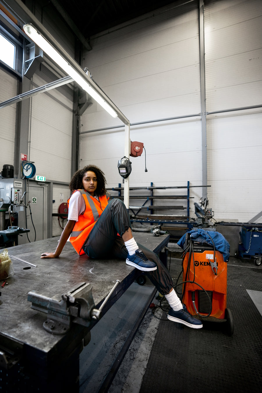 Jongedame met de Jules S2 gecertificeerde veiligheidssneakers in een magazijn, werkschoenen voor dames van DTCH.